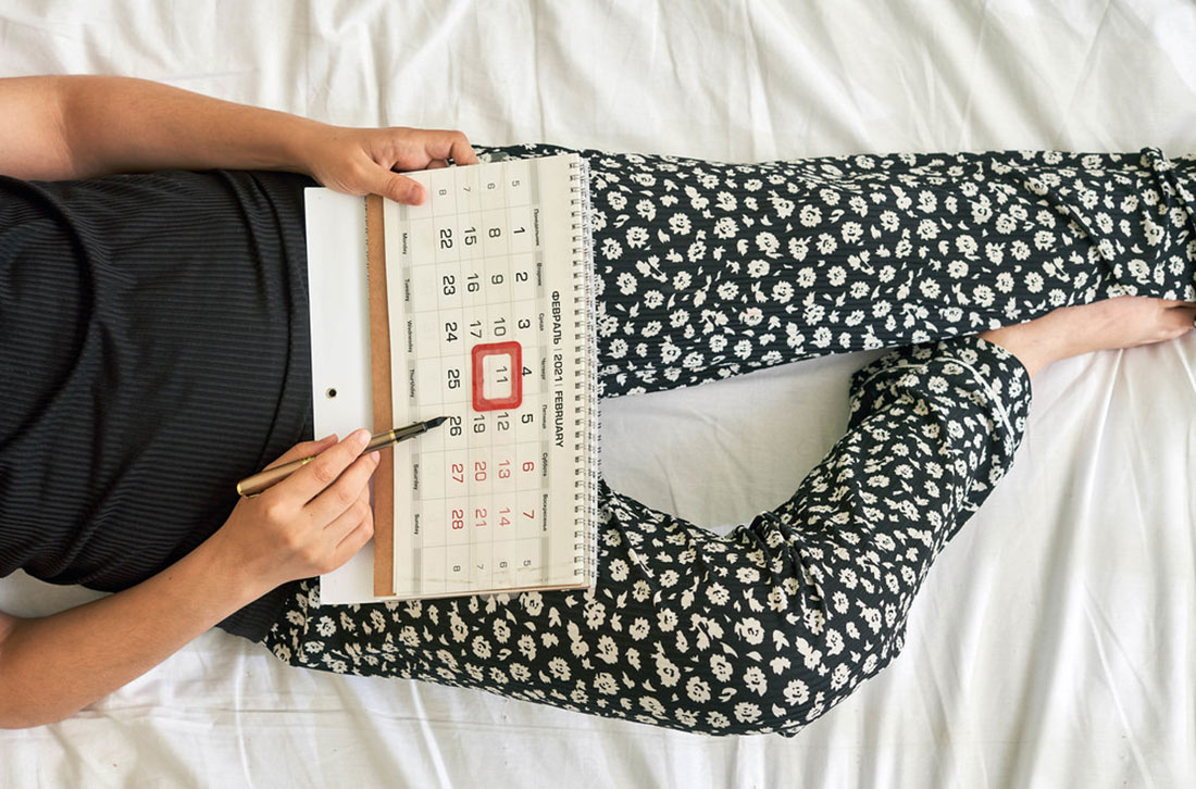 femme allongée avec un calendrier menstruel femme allongée avec un calendrier menstruel